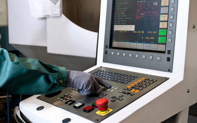 Hand on the control panel of a computer numerical control programmable machine. Milling, CNC technology.